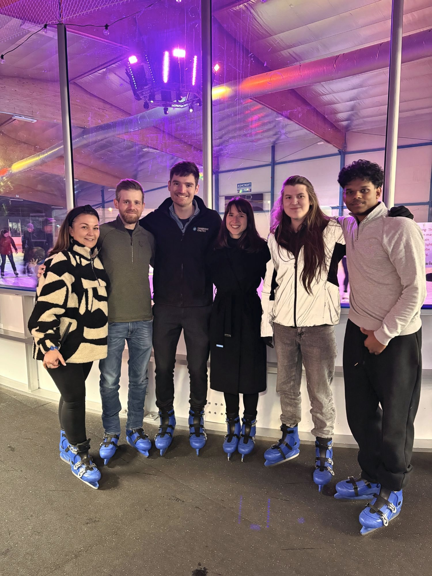 Six of the team in ice skates by the rink on a team night out