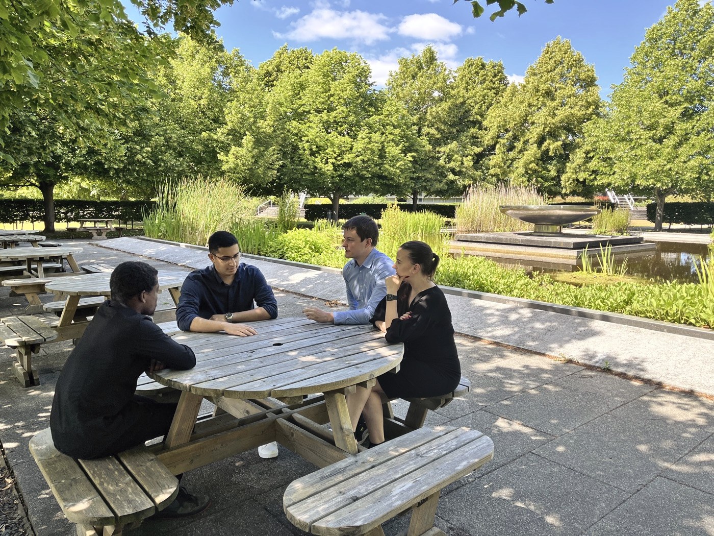 Lunch by the pond Four of the team at a picnic table by the pond outside the office