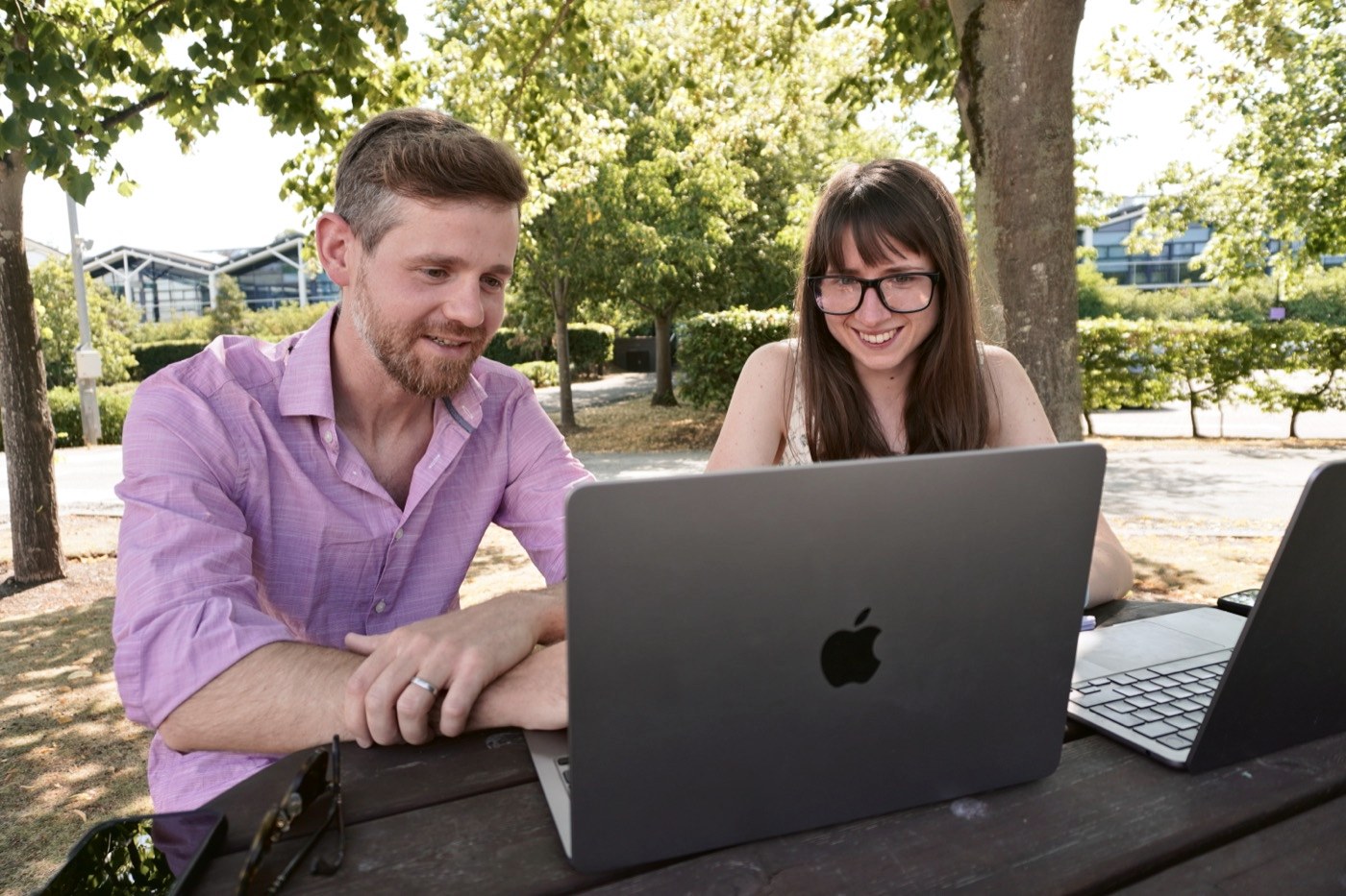 Mike Lewzey and Alena Gorb working through a project together on laptops at a picnic table