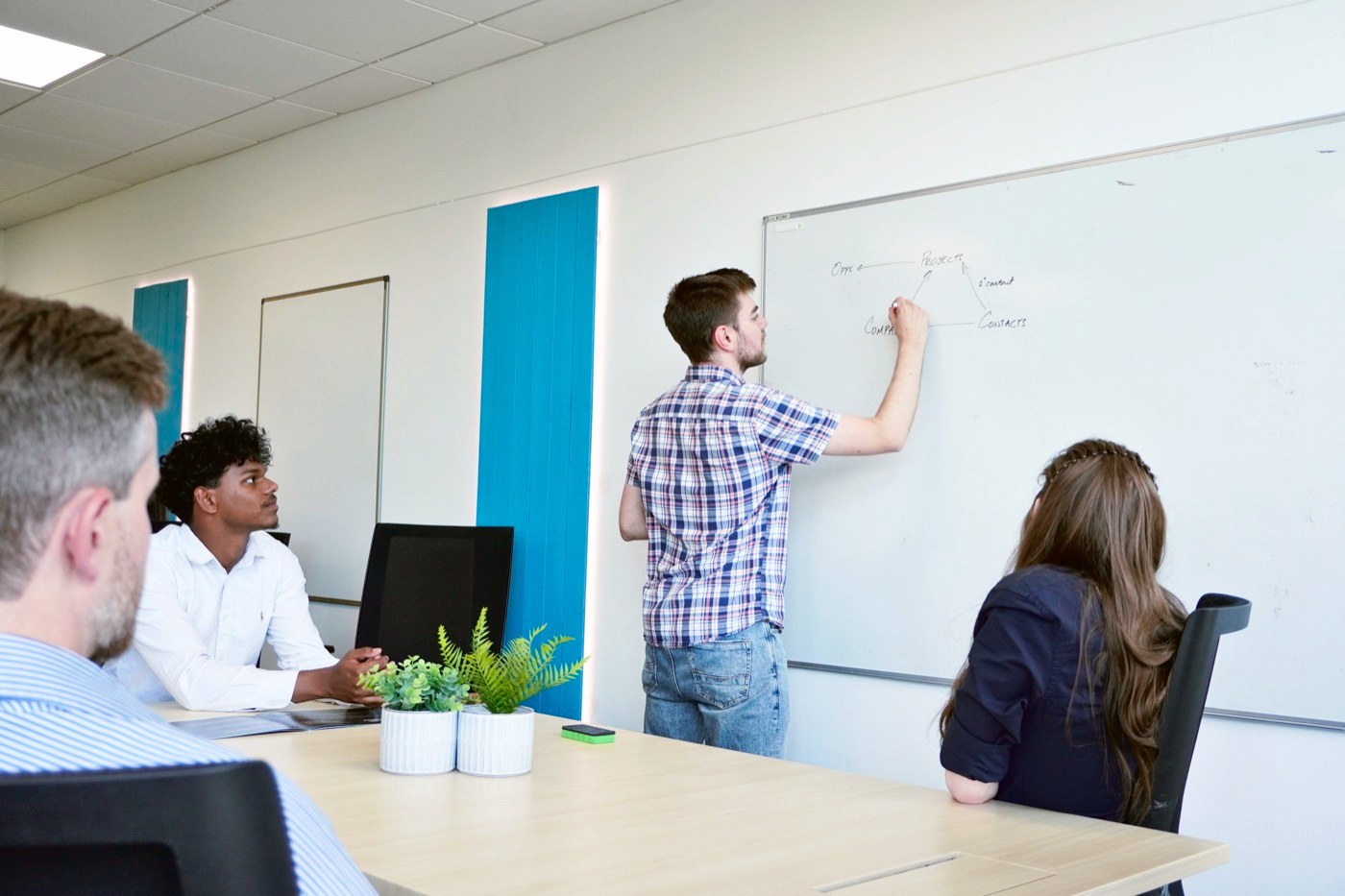 A member of our team sketching on a whiteboard while colleagues look on