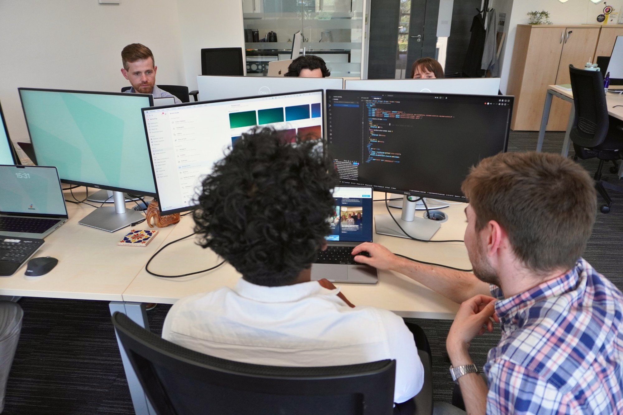 Two of our team building a system together at a desk with two screens
