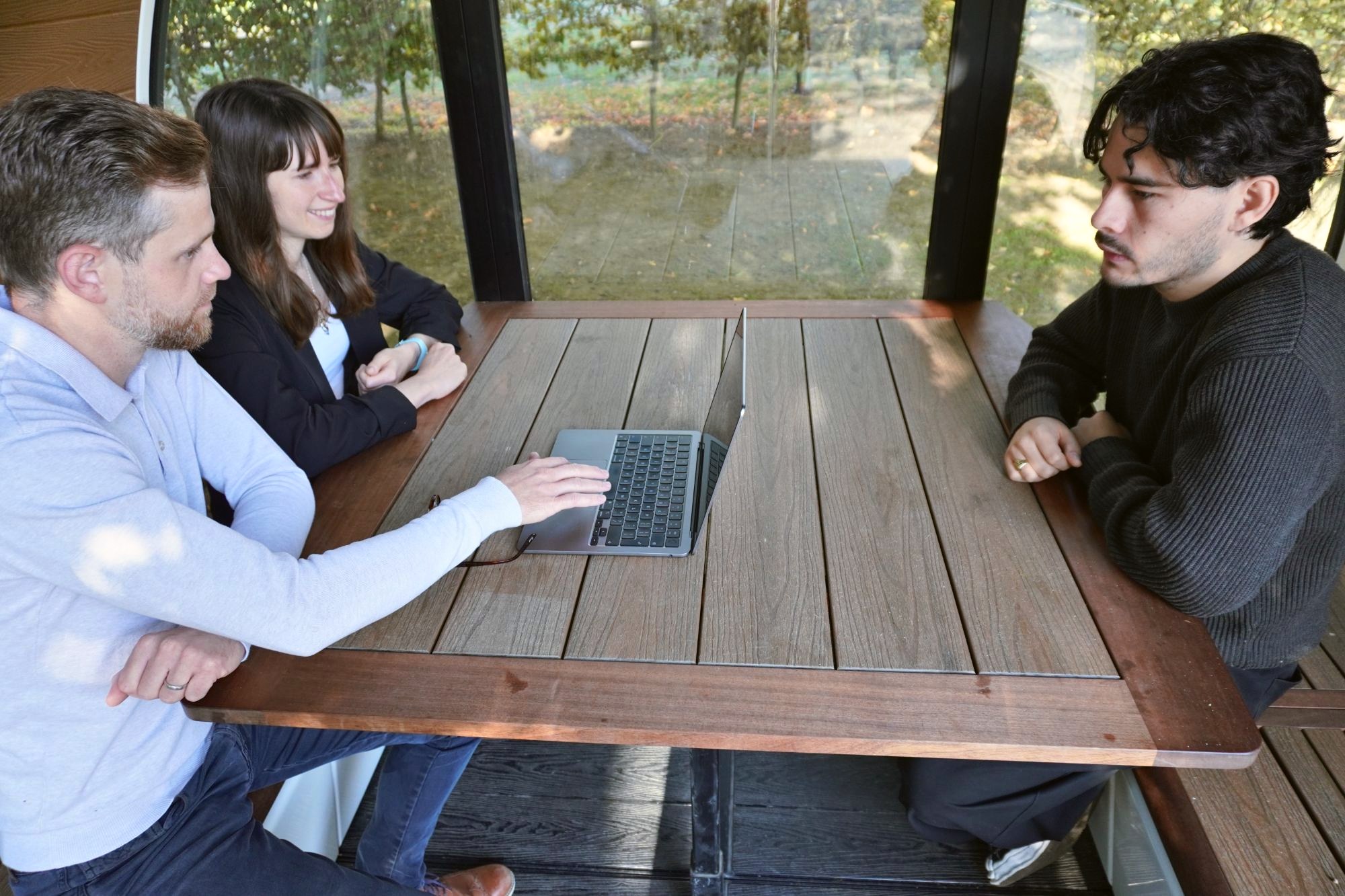 Two of our team showing a client their system on a laptop, in a glass garden pod