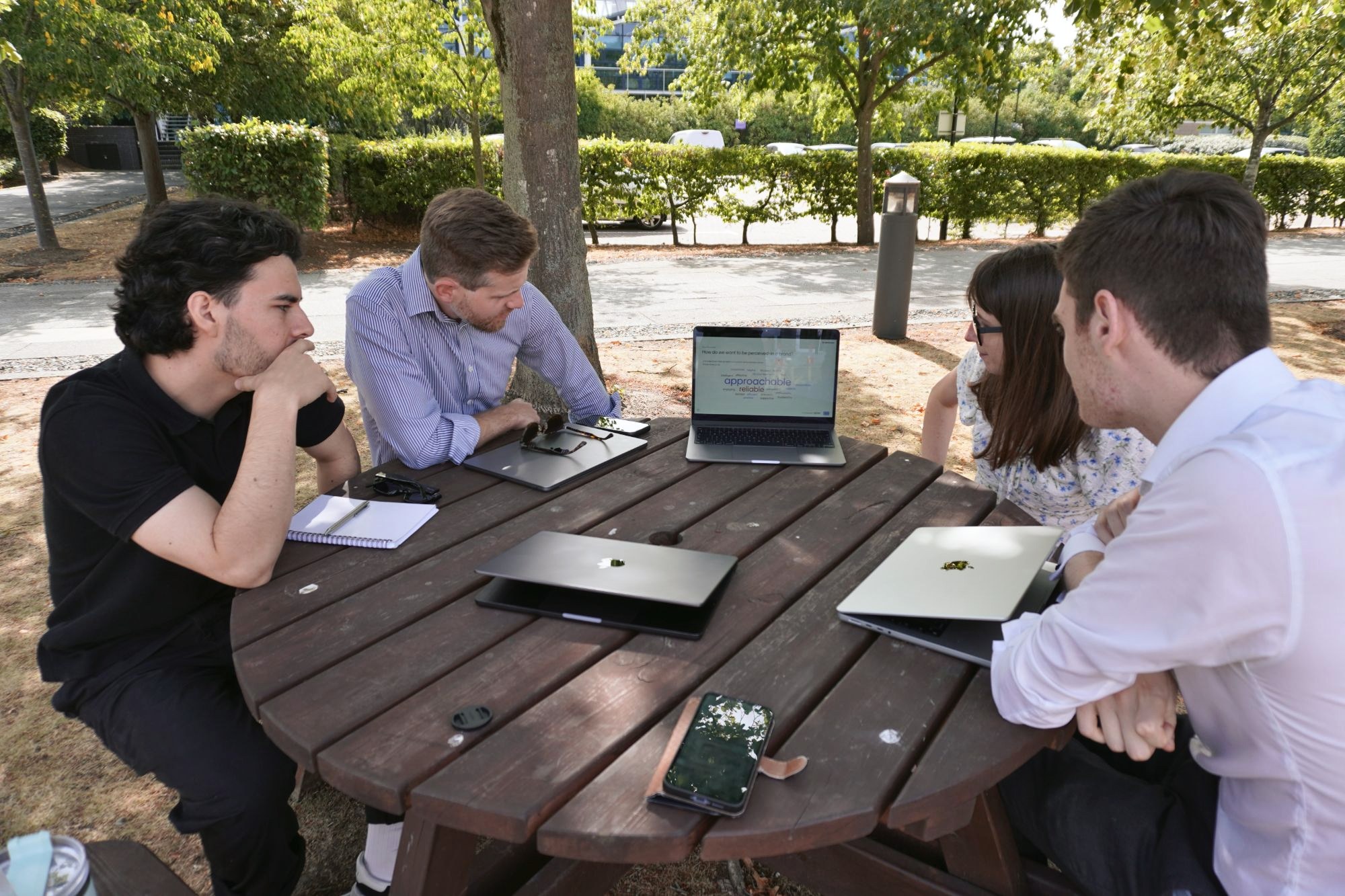 Two of our team working through a client’s processes with them round an outdoor table