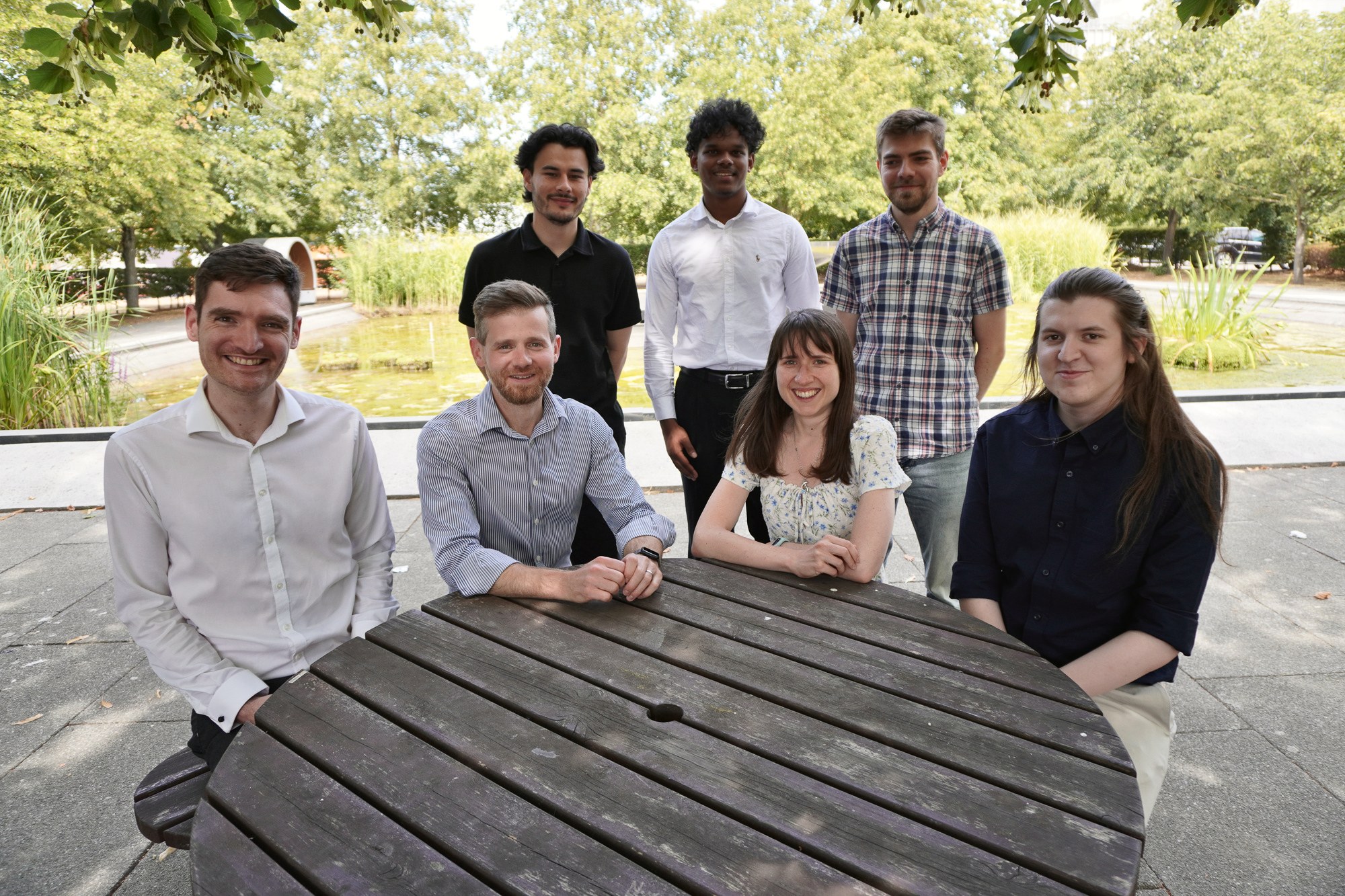 Seven of our team round a picnic table outside our office